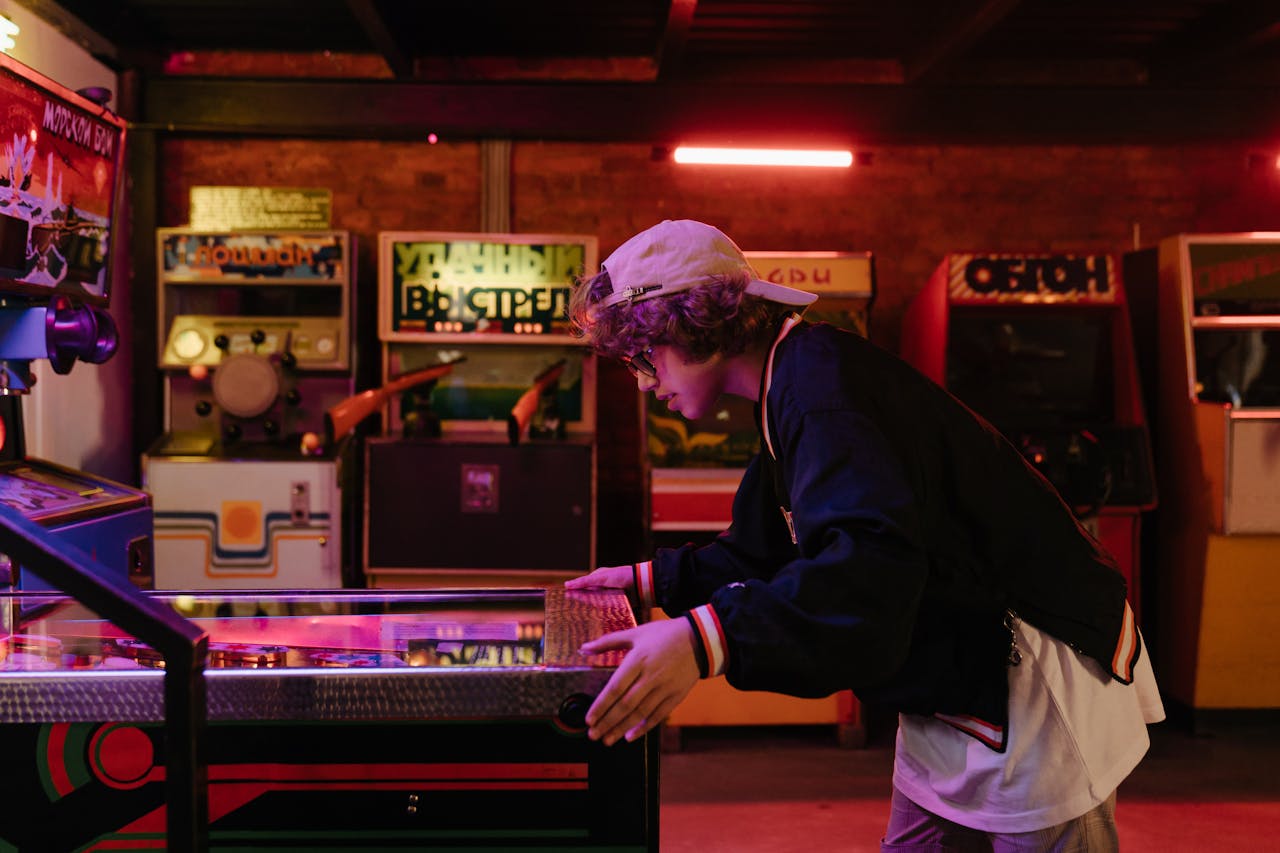 Teenager joyfully playing pinball in a nostalgic retro arcade setting.