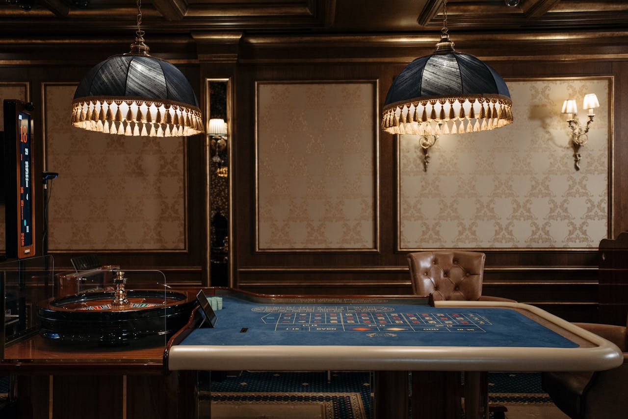 Luxurious casino interior featuring a traditional roulette table under stylish lamps.